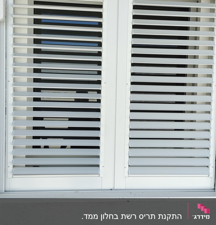 תריסי אלומיניום לבנים על חלון זכוכית